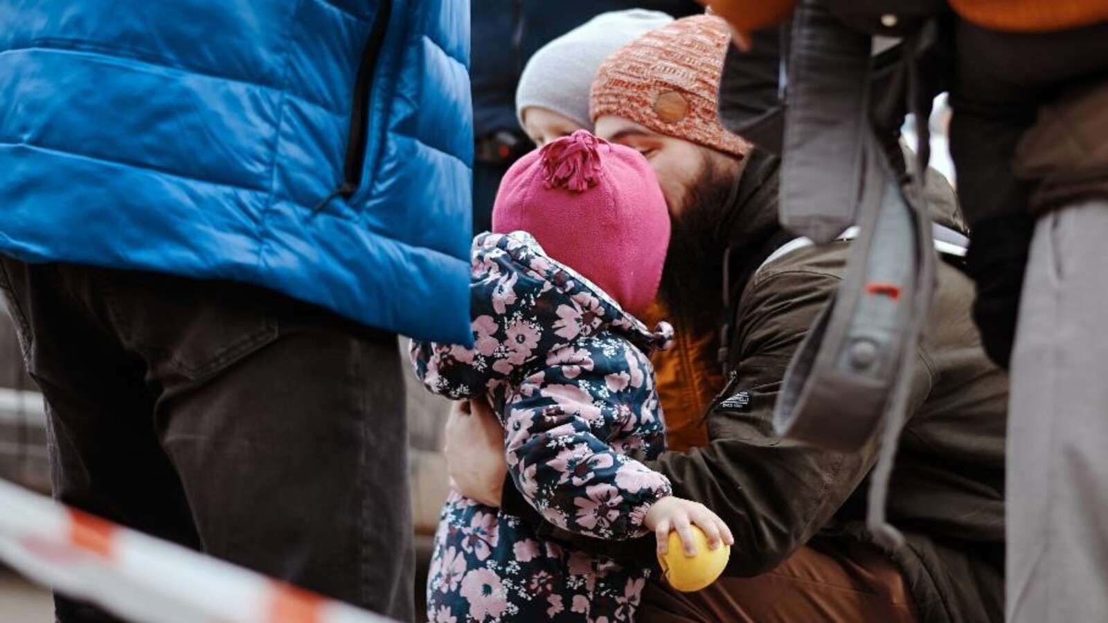 3 bambini con cuffia e giacche a vento, fra due adulti