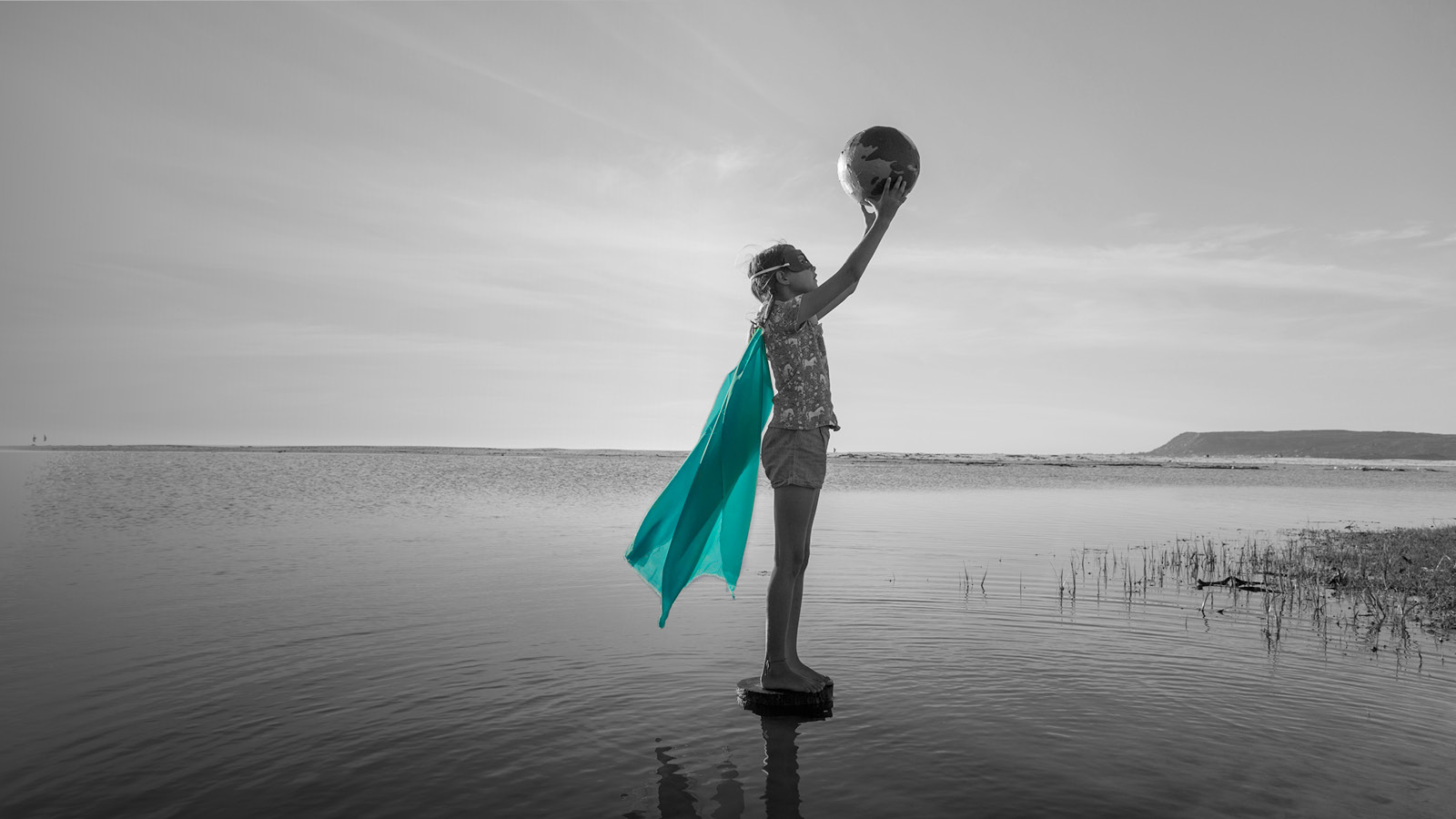 Immagine di bambina con mappamondo e mantello da Super Eroina